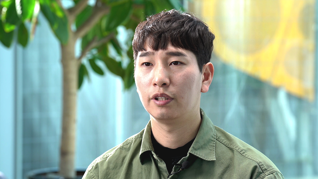 a man with short hair wearing a green shirt