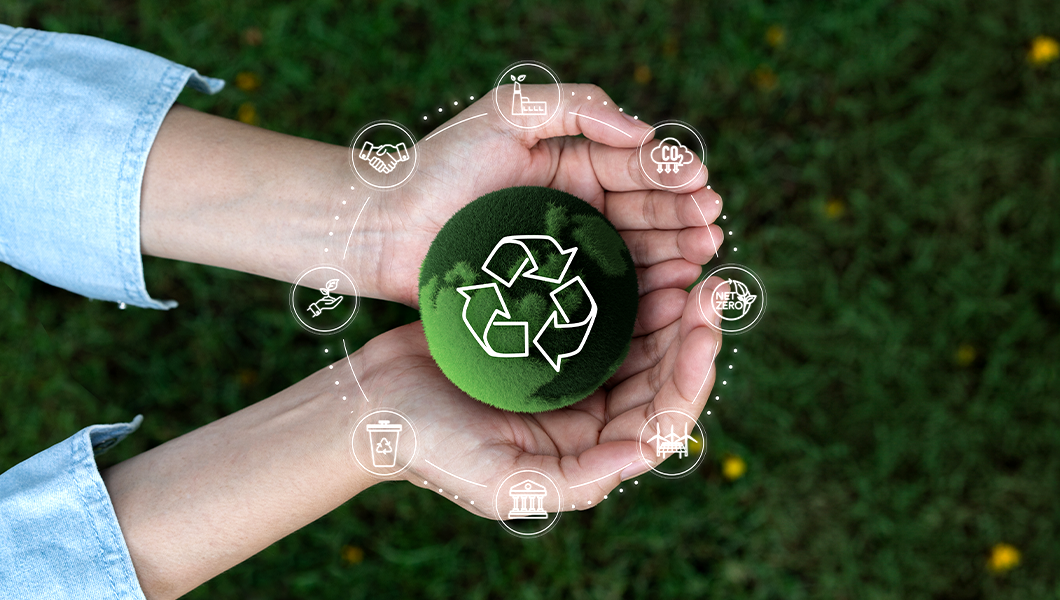hands holding a green ball with a recycle symbol around it